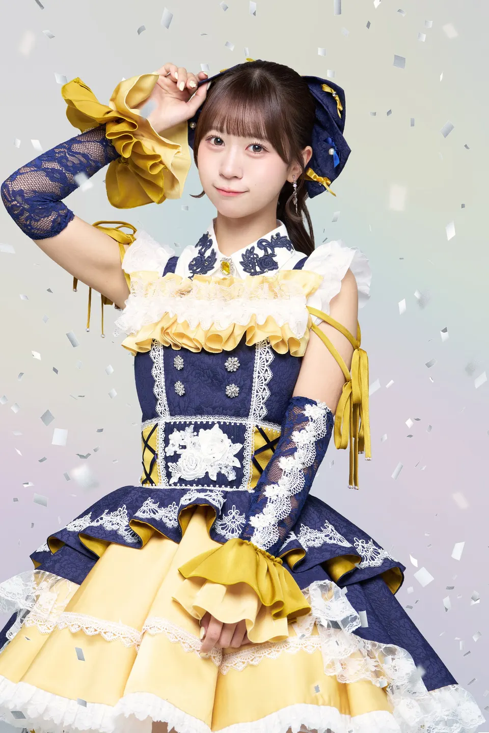 Arisa Takanashi poses with one hand beside her head in a navy, white and yellow ruffled stage costume.