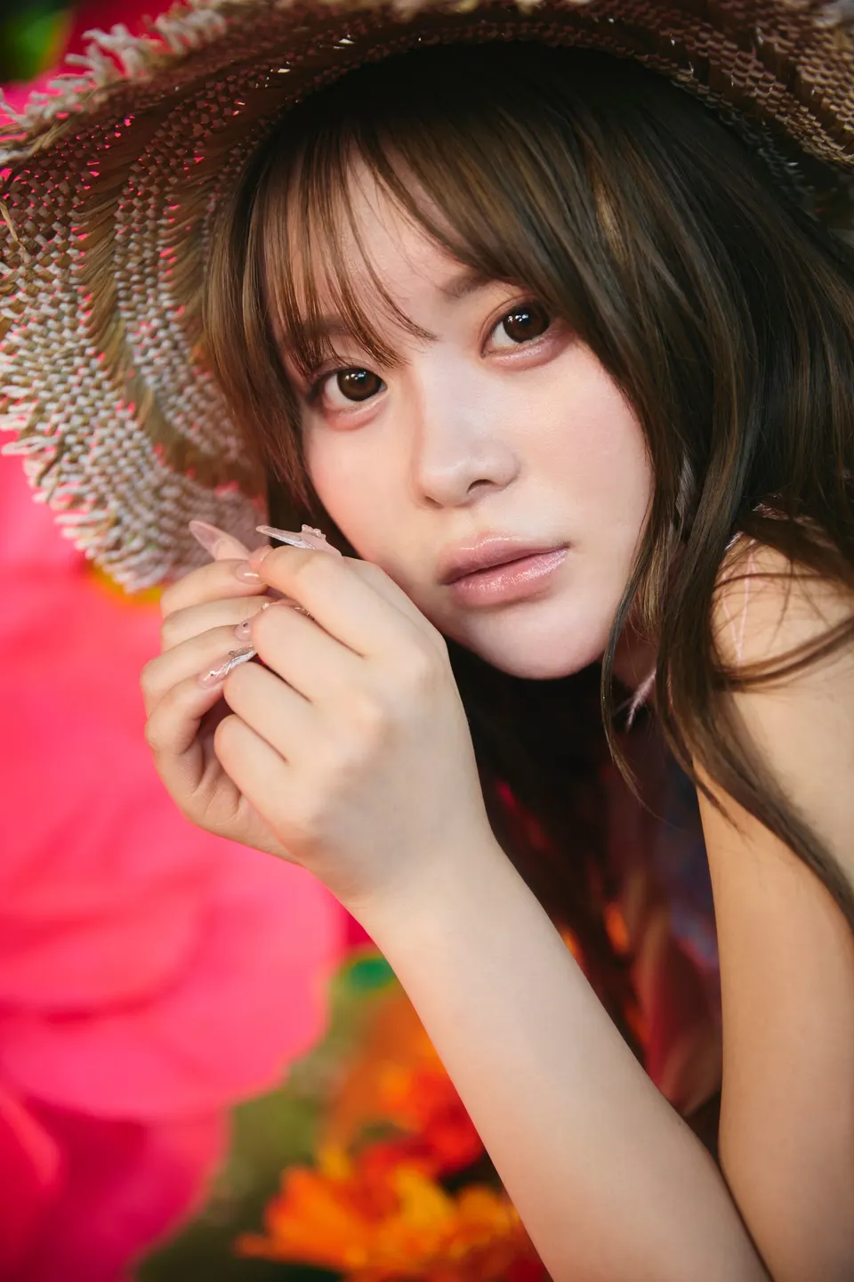 Sakura (さくら) beneath a woven hat, holding her hands beside her face.
