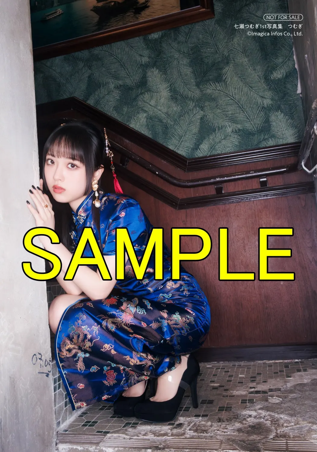 Seven Net photographic print sample for Tsumugi, showing Tsumugi Nanase in a blue Chinese-style dress beside a column and dark wooden paneling, marked SAMPLE.