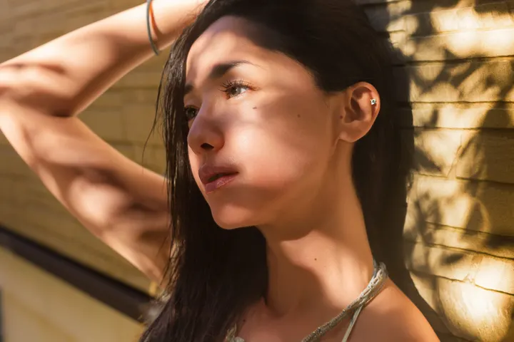 Erika Sawajiri (沢尻エリカ) beside a yellow textured wall, with one arm raised and sunlight casting shadows across her face.
