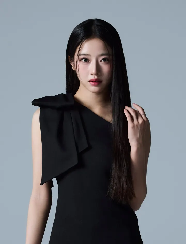 Amane Tensho (天翔天音) wearing a black one-shoulder outfit with a large bow against a gray background.