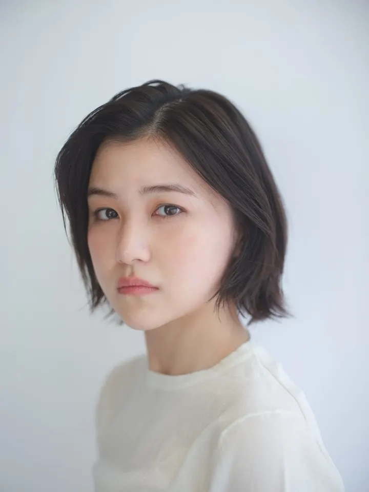 Mayu Yamaguchi in a pale high-neck top against a light gray background.