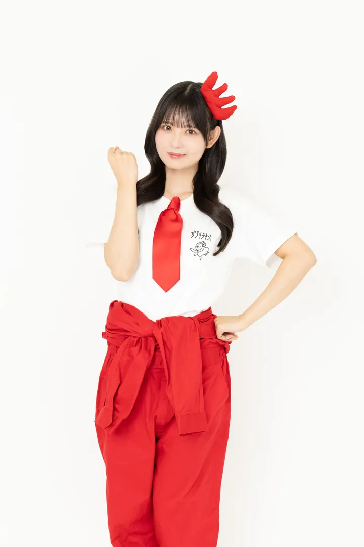 Miki Ito (伊藤実希) wearing a white campaign T-shirt, red tie, red trousers and a red head accessory, with one fist raised and her other hand at her hip against a white background.