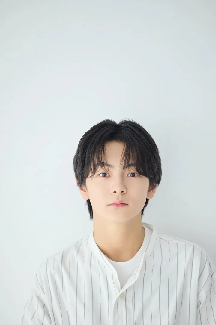 Jun Saito wearing a pale striped shirt over a white T-shirt against a light background.