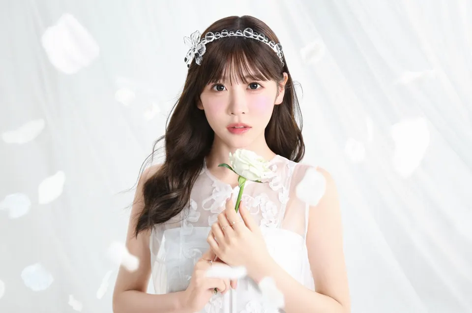 Yui Sakurai (櫻井優衣) holds a white flower, wearing a white outfit and a clear decorative headband against a pale background.