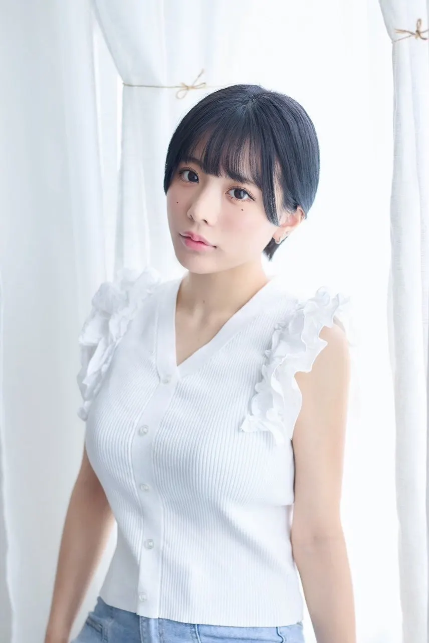 hananojk (鼻のjk) with short dark hair, wearing a white buttoned top with ruffled shoulders beside white curtains.