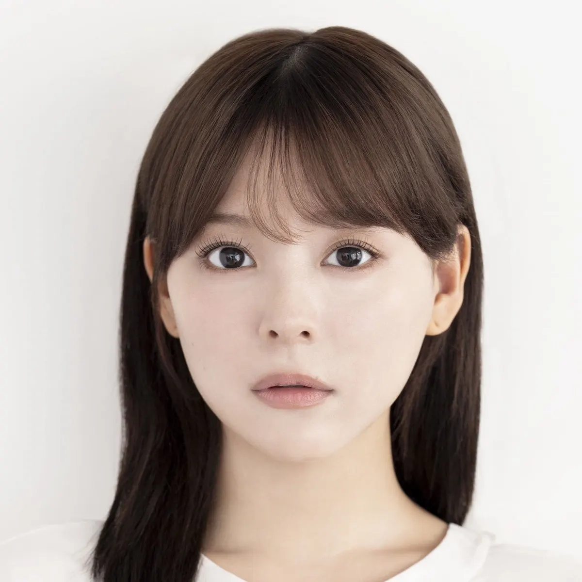 Nagisa Saito facing the camera in a white top, with straight dark hair and bangs against a pale background.