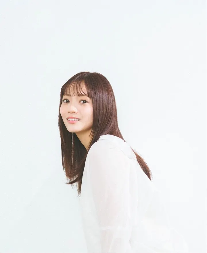 Manamo Miyata (宮田愛萌) wearing a white blouse and looking toward the camera against a pale background.
