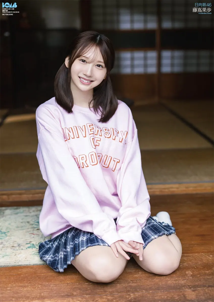 One side of the BOMB November 2026 regular-edition poster, showing Kaho Fujishima (藤嶌果歩) kneeling on a wooden floor in a pink sweatshirt and checked skirt.