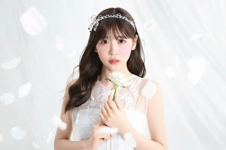 Yui Sakurai (櫻井優衣) holds a white flower, wearing a white outfit and a clear decorative headband against a pale background.