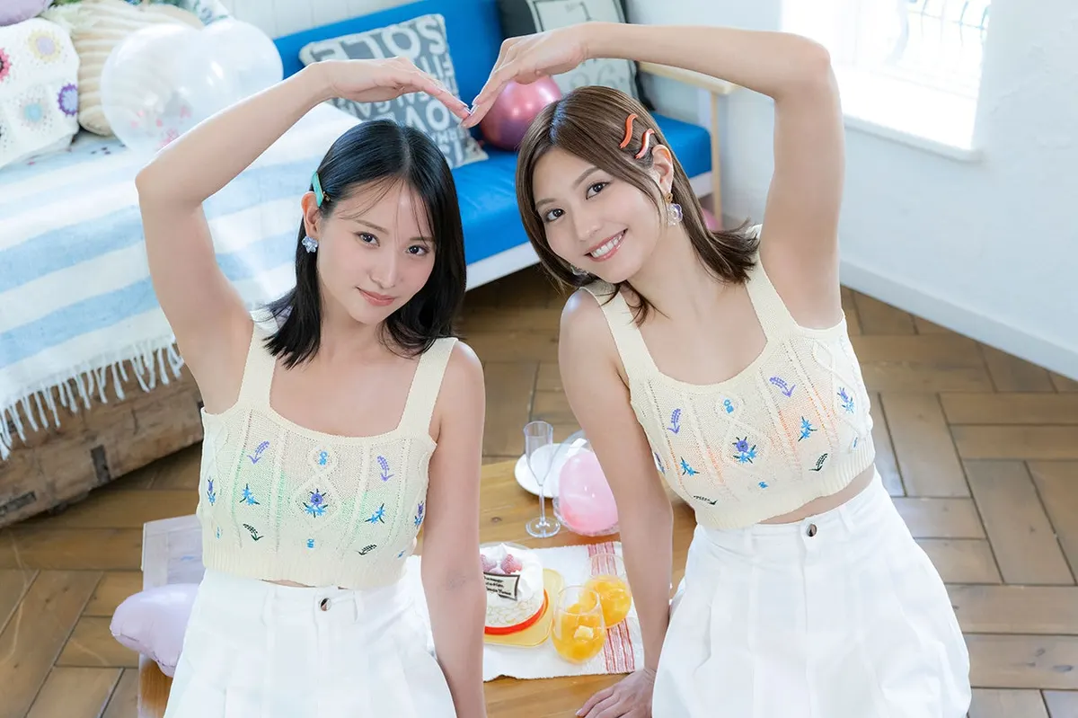 Mariya Nagao (永尾まりや) and Yume Hayashi form a heart with their raised arms, wearing cream embroidered tops and white shorts beside cake, drinks and balloons.