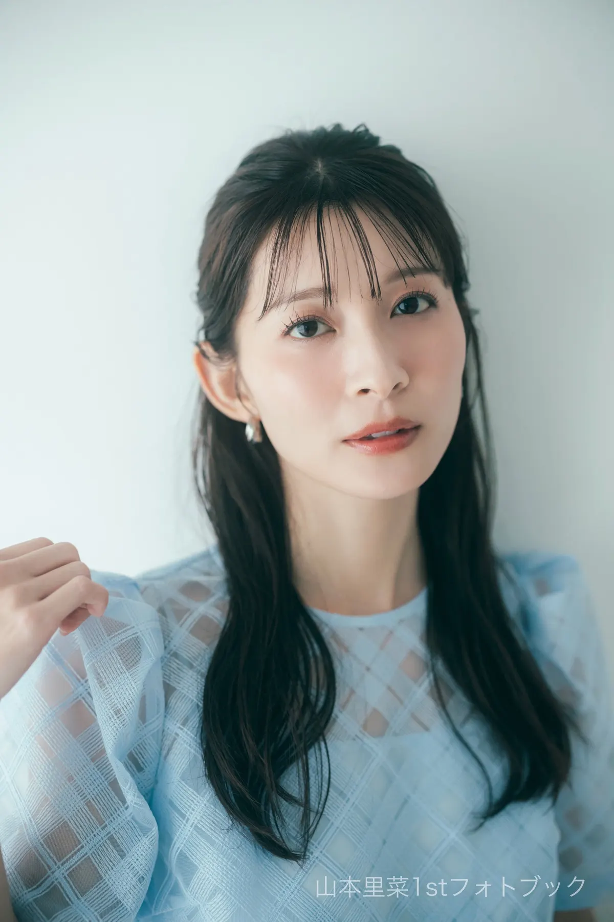 Rina Yamamoto (山本里菜) looking toward the camera in a light-blue patterned sheer top, with one hand raised near her shoulder.
