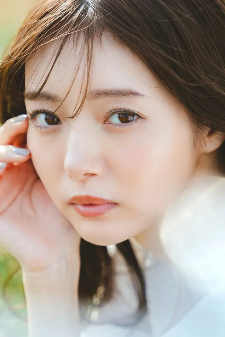 Close portrait of Miori Ichikawa (市川美織) in pale clothing with one hand beside her face.
