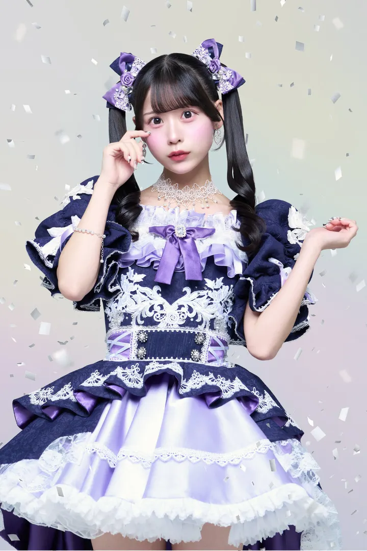 Miyuu Oguri wears a navy, white and purple lace stage costume with purple bows in her twin ponytails.