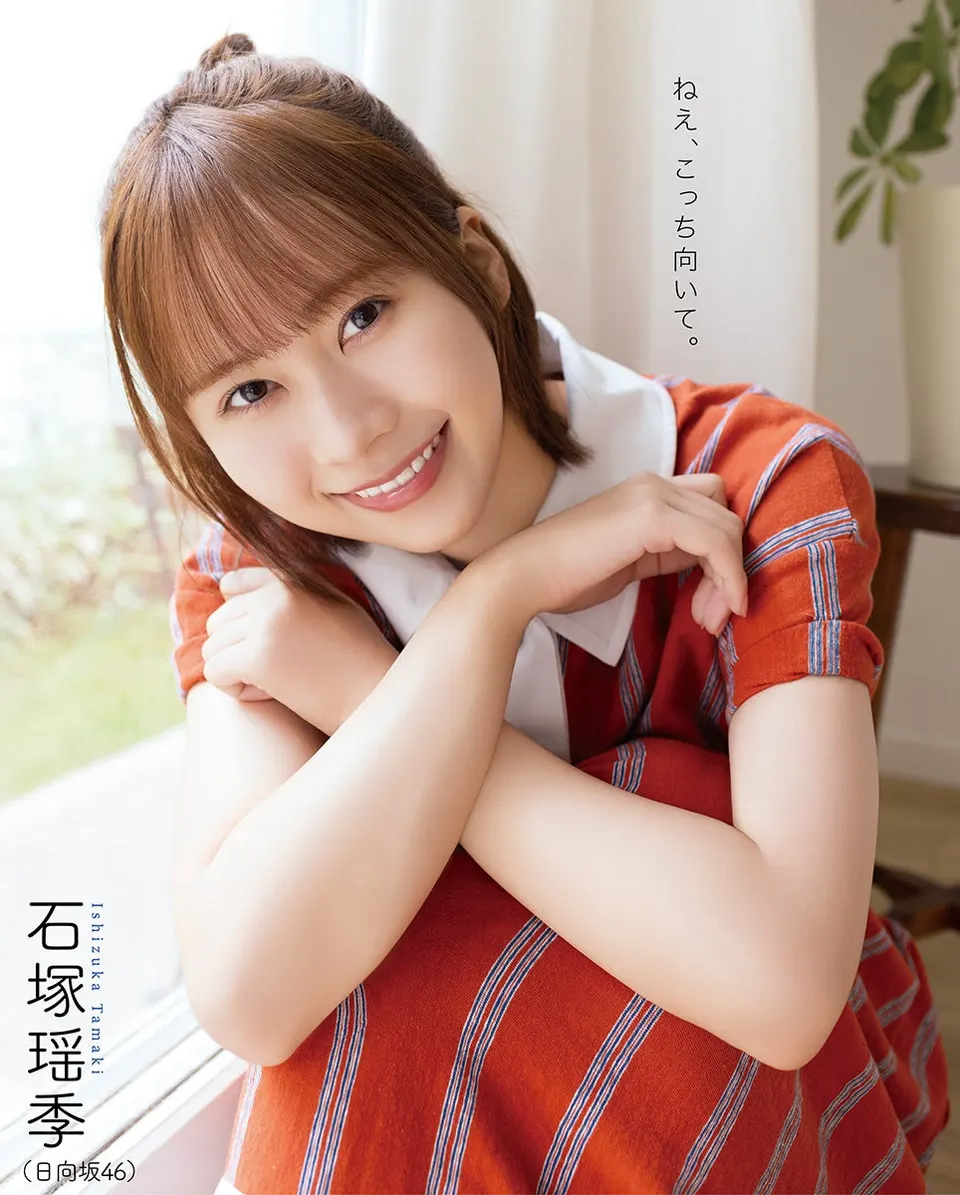 Tamaki Ishizuka (石塚瑶季) smiling beside a window in an orange striped dress with a white collar, on BOMB November 2026 back-cover artwork.