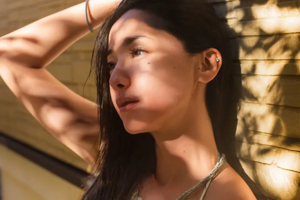 Erika Sawajiri (沢尻エリカ) beside a yellow textured wall, with one arm raised and sunlight casting shadows across her face.